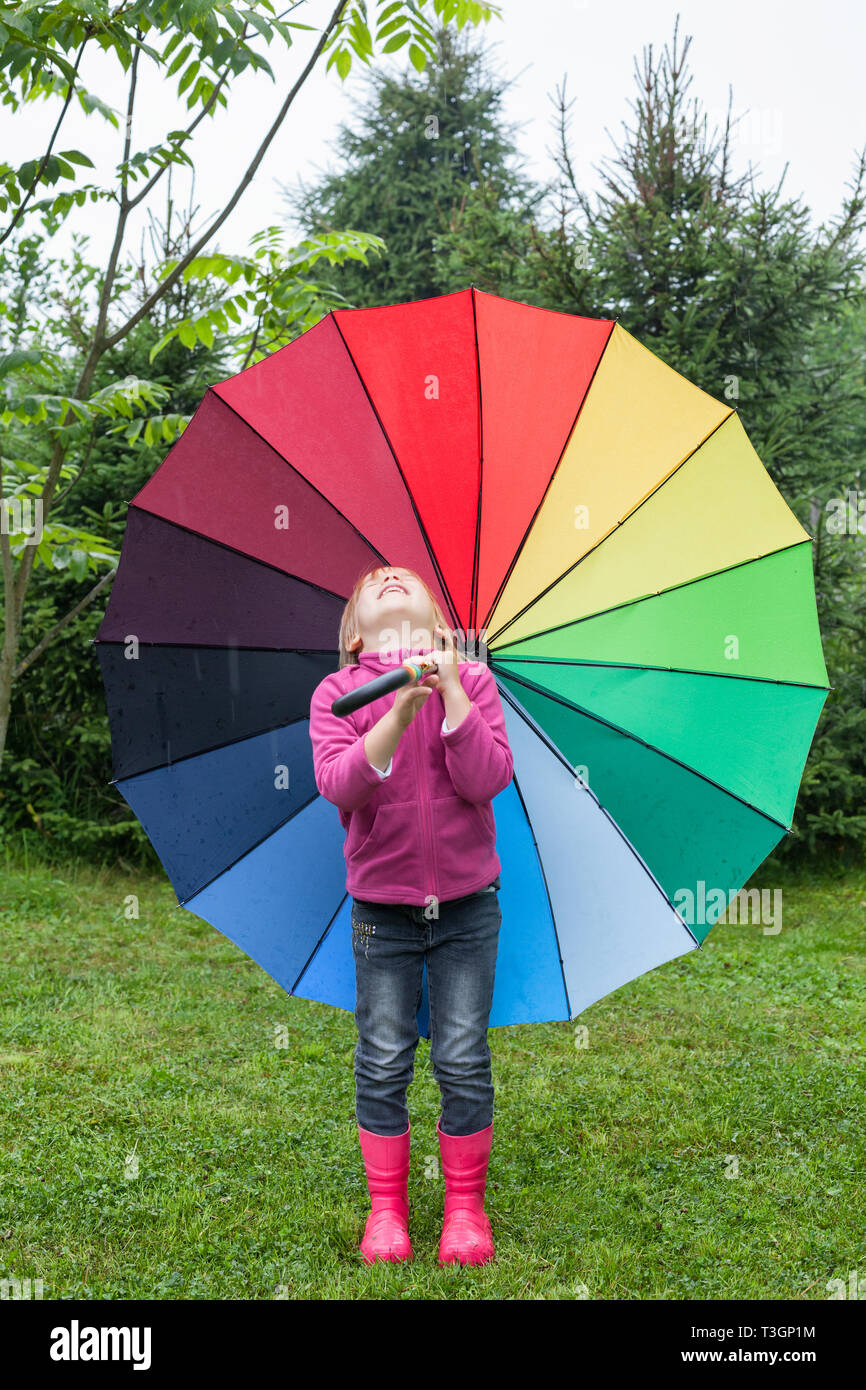 Little girl wearing fleece jacket and rubber boots standing with