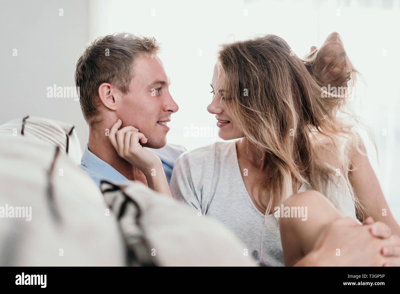 young couple embracing while sitting face to face on a couch Stock Photo