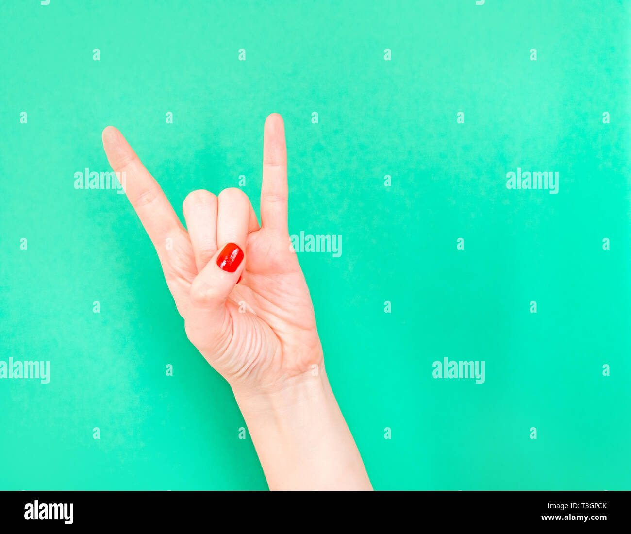 Woman hand shows Rock N Roll Hand Signs isolated on turquoise green ...
