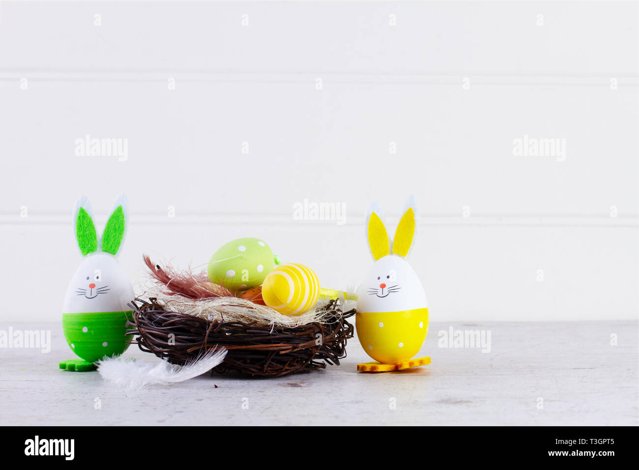 Easter scene with colored eggs in nest and green rabbit, copy space ...