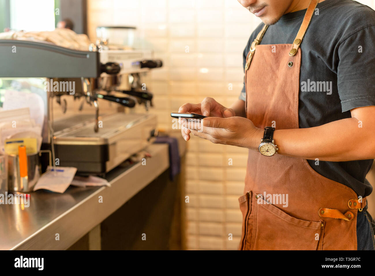 Barista checking cell phone in coffee shop. Stock Photo