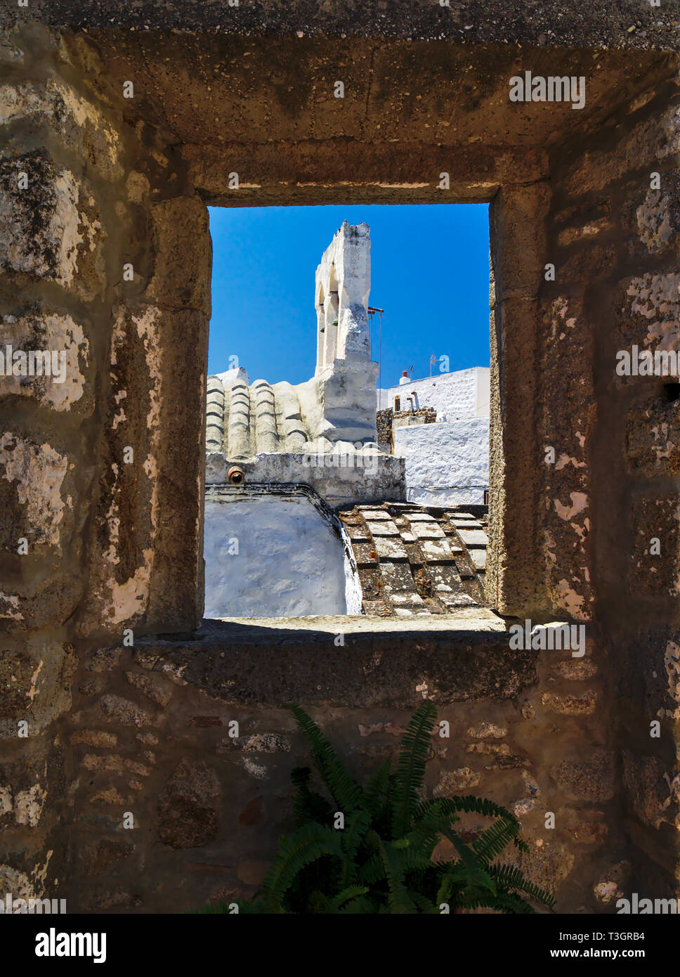 Church bell tower in Patmos island in Greece. Bell tower framed through a window. Stock Photo