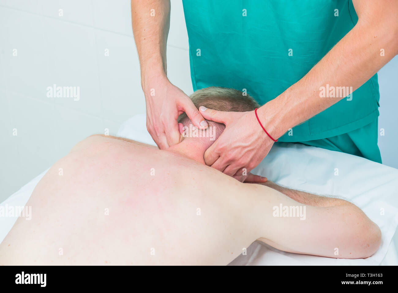 Physiotherapist massaging male patient with injured neck muscle. Sports injury treatment, reabilitation. Neurological physical examination. Osteopathy Stock Photo