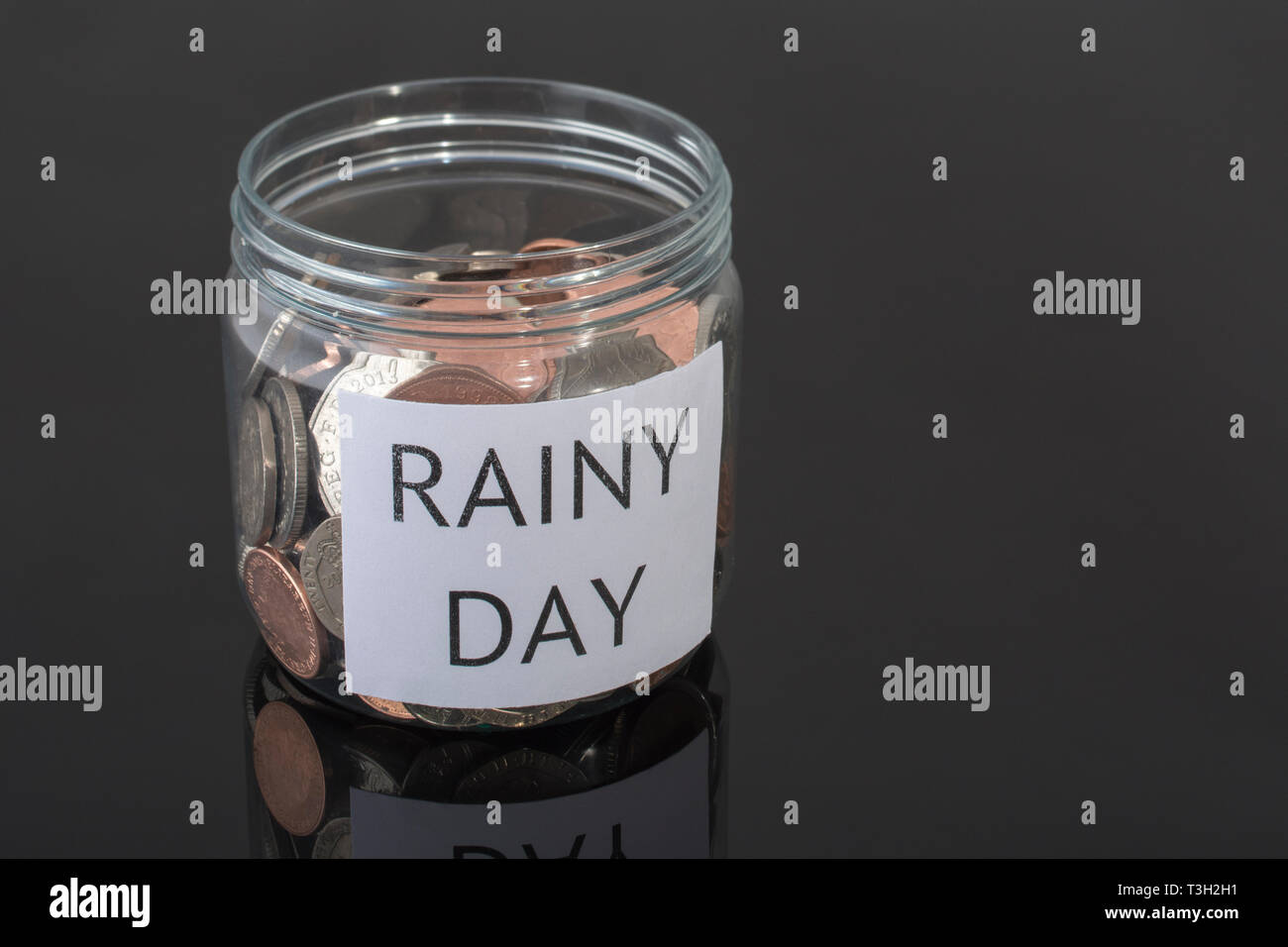 Plastic pot containing UK coins. Metaphor personal savings, rainy day saving, pensions savings pot, retirement savings, saving for retirement . Stock Photo