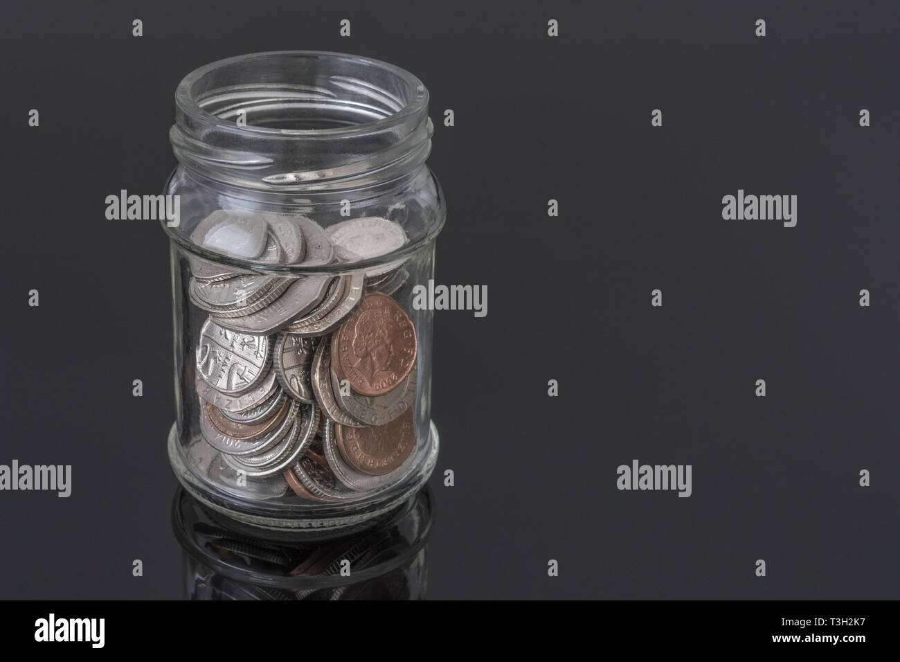 Glass jar containing UK coins - as metaphor for personal savings, rainy day saving, pensions savings pot, saving pot. Stock Photo