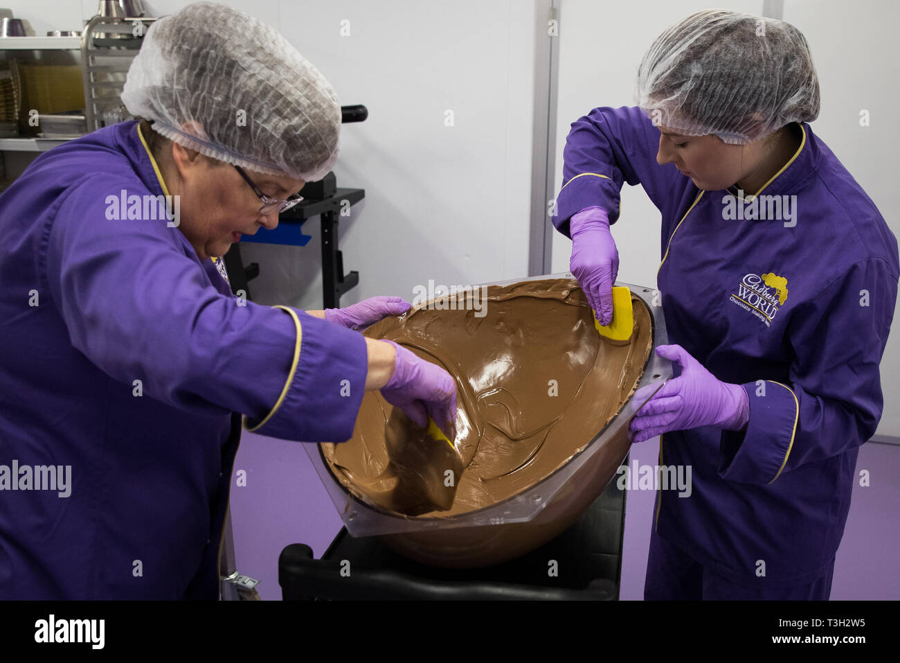 Chocolatiers spread tempered chocolate as they create a giant chocolate egg at Cadbury World in Birmingham to celebrate Easter. Stock Photo