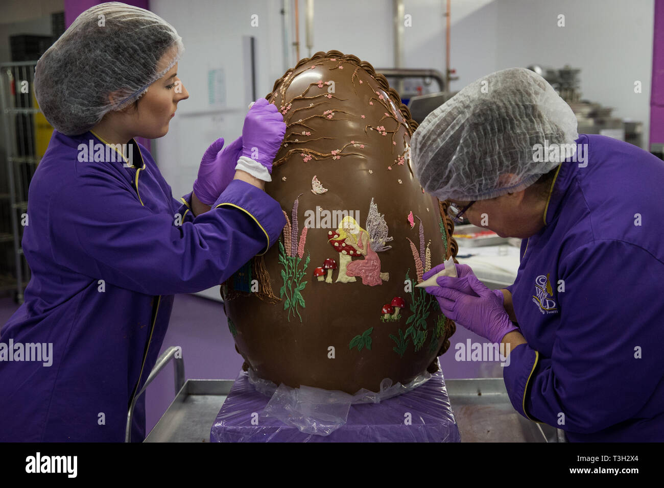 Chocolatiers decorate a giant chocolate egg at Cadbury World in Birmingham to celebrate Easter. Stock Photo