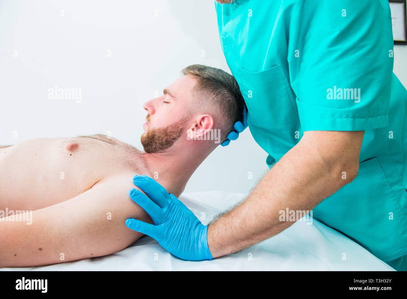 Male patient receiving massage from therapist. A chiropractor stretching his patient's neck in medical office. Neurological physical examination. Oste Stock Photo