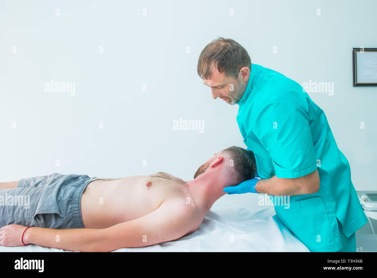 Male patient receiving massage from therapist. A chiropractor stretching his patient's neck in medical office. Neurological physical examination. Oste Stock Photo