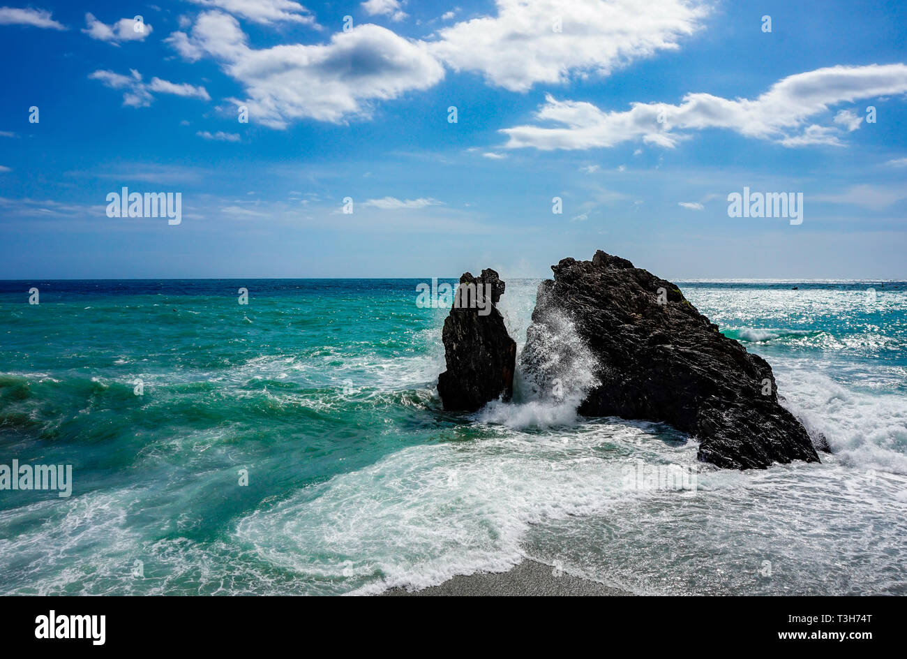 Big rock in the mediterrean sea between the waves crashing a big wave Stock Photo