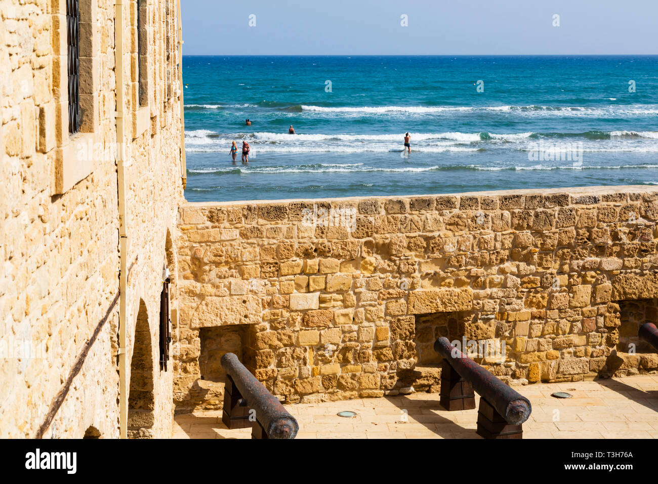 Courtyard of Larnaca Fort looking over the walls to the sea beyond with bathers in the surf.Cyprus October 2018 Stock Photo