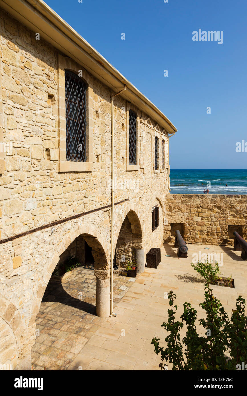 Courtyard of Larnaca Fort looking over the walls to the sea beyond with bathers in the surf.Cyprus October 2018 Stock Photo