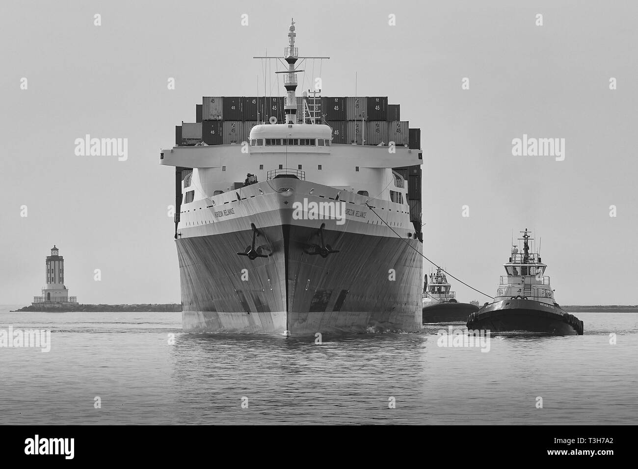 Black And White Photo Of The PASHA HAWAII, Container Ship, HORIZON RELIANCE, Enters The Los Angeles Main Channel At The Angels Gate Lighthouse Stock Photo