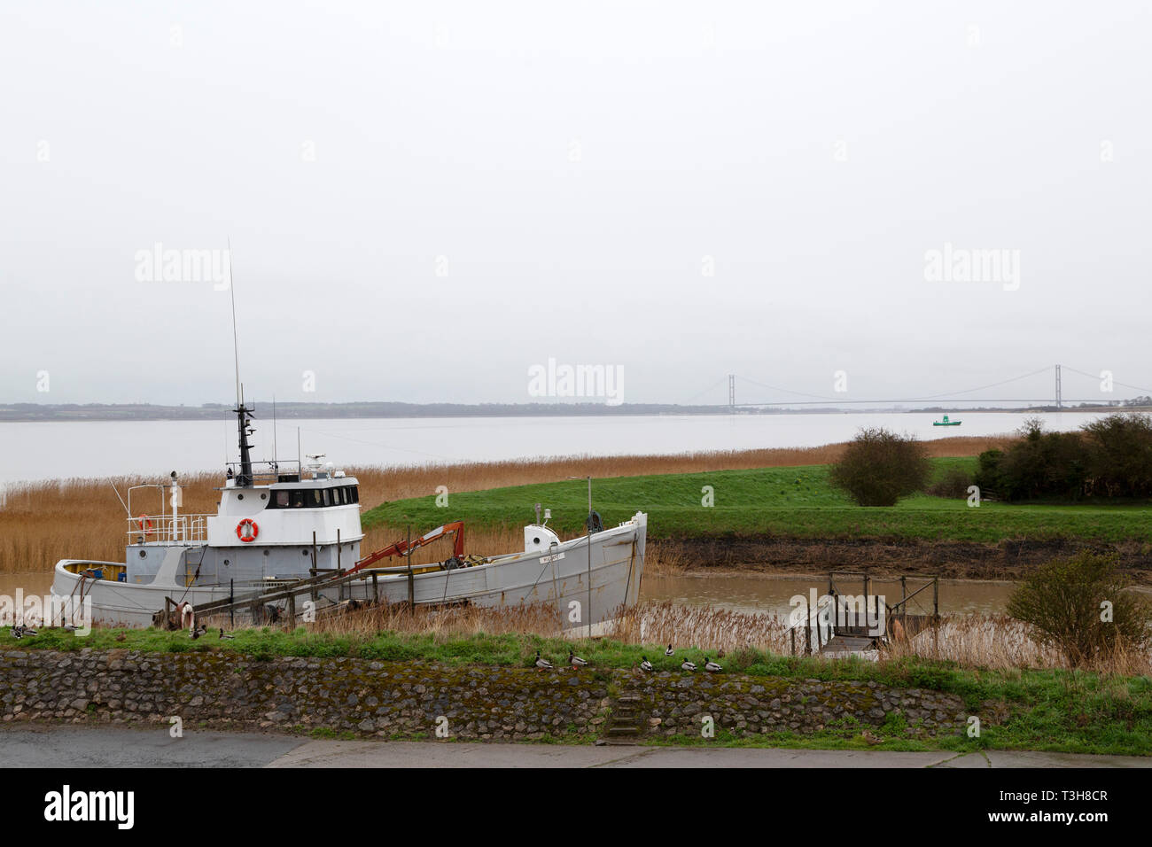 Fishing boat docked by the River Humber in North Lincolnshire. The Humber Bridge can be seen in the distance. Stock Photo