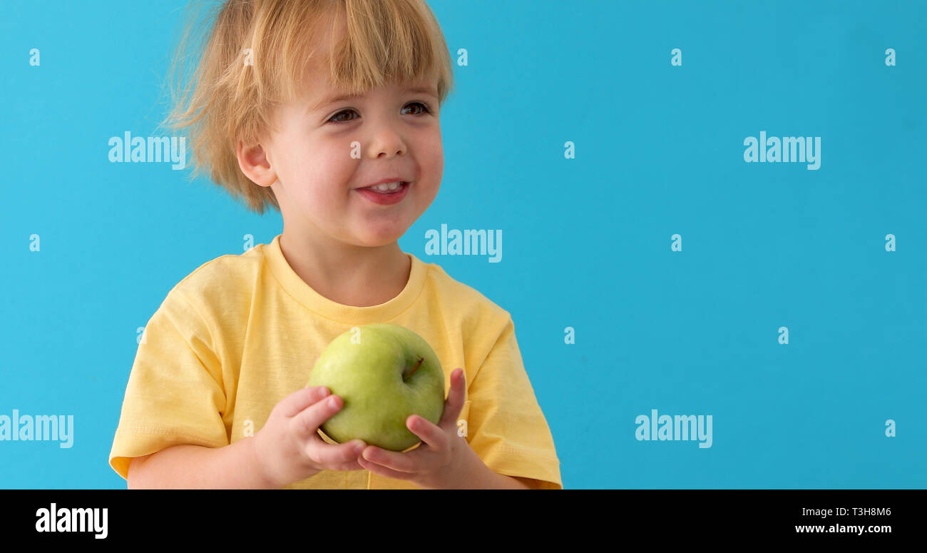small boy holds a big green apple Stock Photo