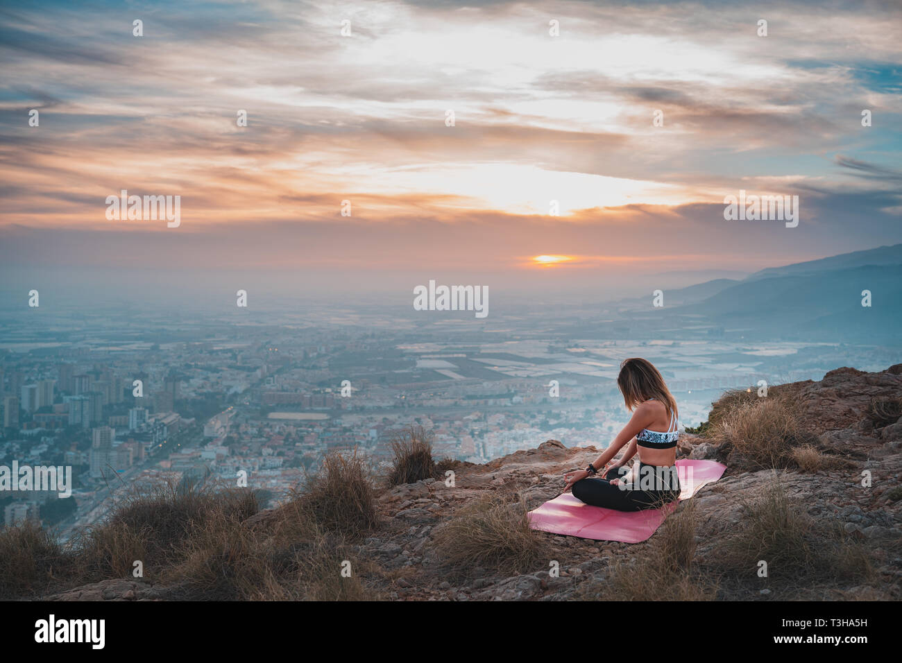 Beautiful young woman doing yoga at the top of the mountain with views ...