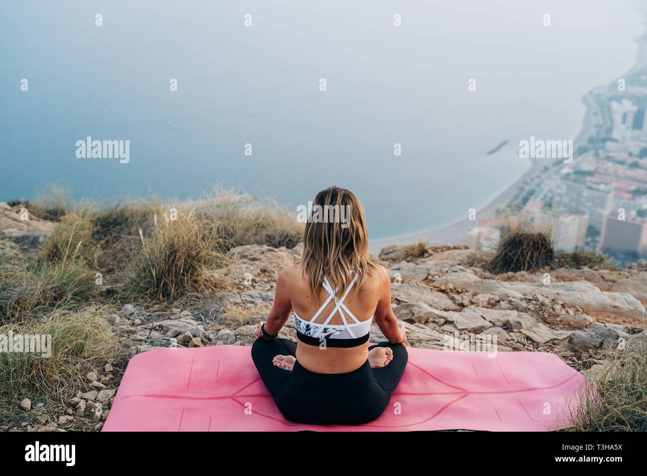 Beautiful young woman doing yoga at the top of the mountain with views ...