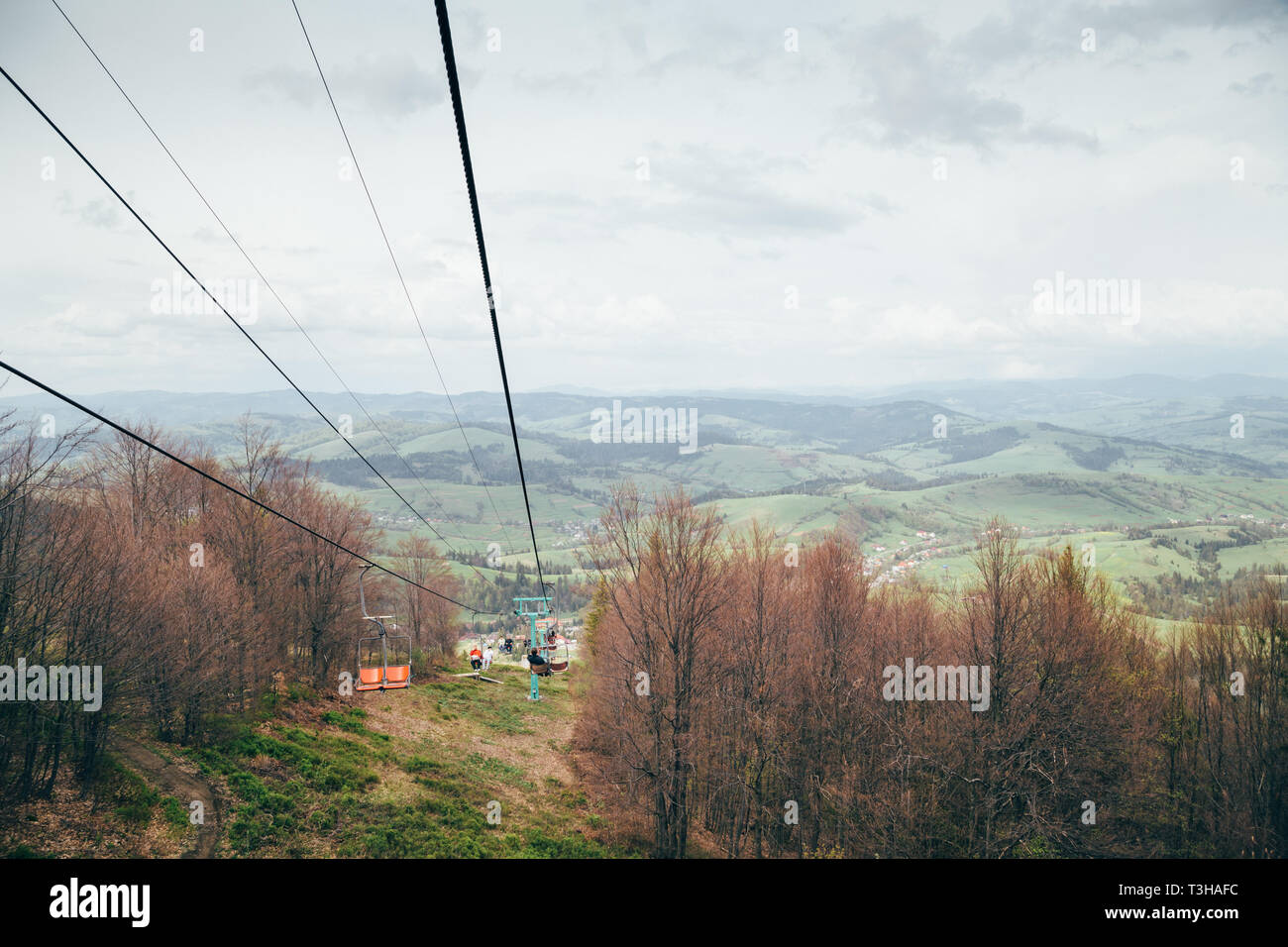 A view from a cablecar, cableway at mountains surrounded by forest going down to the meadow Stock Photo