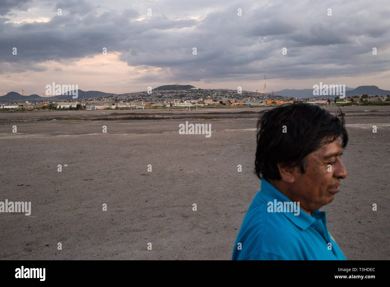 A man walks across an area of land that was once part of Lake Texcoco, in Chimalhuac‡n, the State of Mexico, Mexico, August 24, 2017. A group of local residents are engaged in a land dispute over this land, which they call ÒTlatelesÓ, or Òmountain of sandÓ which the Mexican Federal Government wanted to use for the new Mexico City International Airport project. Mexico's newly elected president Andreas Lopez Manuel Obrador cancelled this project in the fall of 2018, while it was in the middle of construction. The airport was set to replace the aging Benito Juarez International Airport. Stock Photo