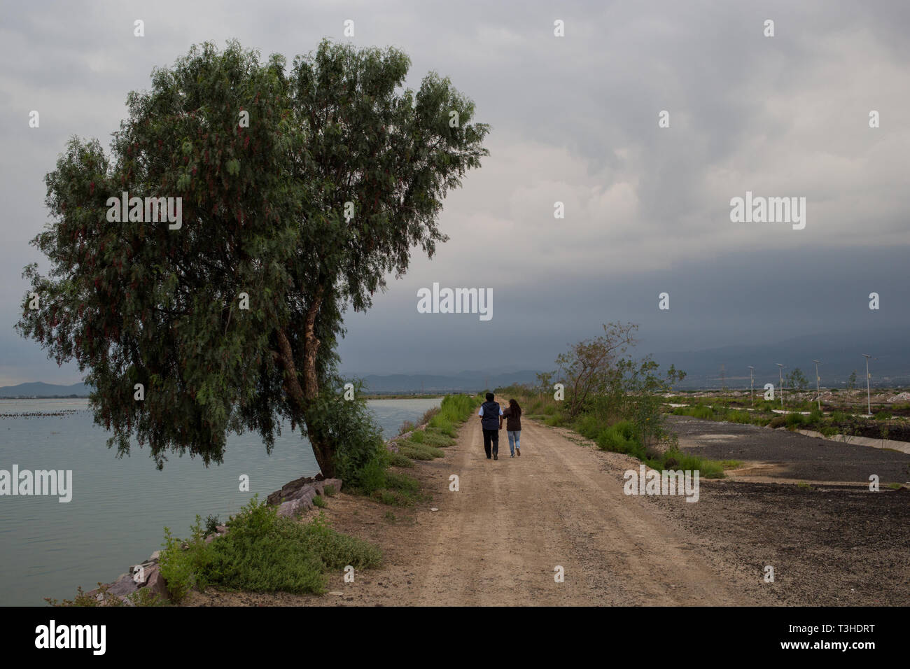 People walk beside Lake Texcoco, in the State of Mexico, Mexico, August 25, 2017. The new Mexico City International Airport is being constructed on the far side of Lake. Mexico's newly elected president Andreas Lopez Manuel Obrador cancelled this project in the fall of 2018, while it was in the middle of construction. The airport was set to replace the aging Benito Juarez International Airport. Stock Photo