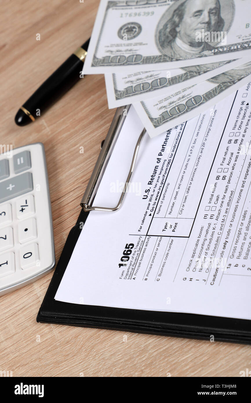 1065 tax form lies near hundred dollar bil and calculator  on a Table. US Return for parentship income Stock Photo