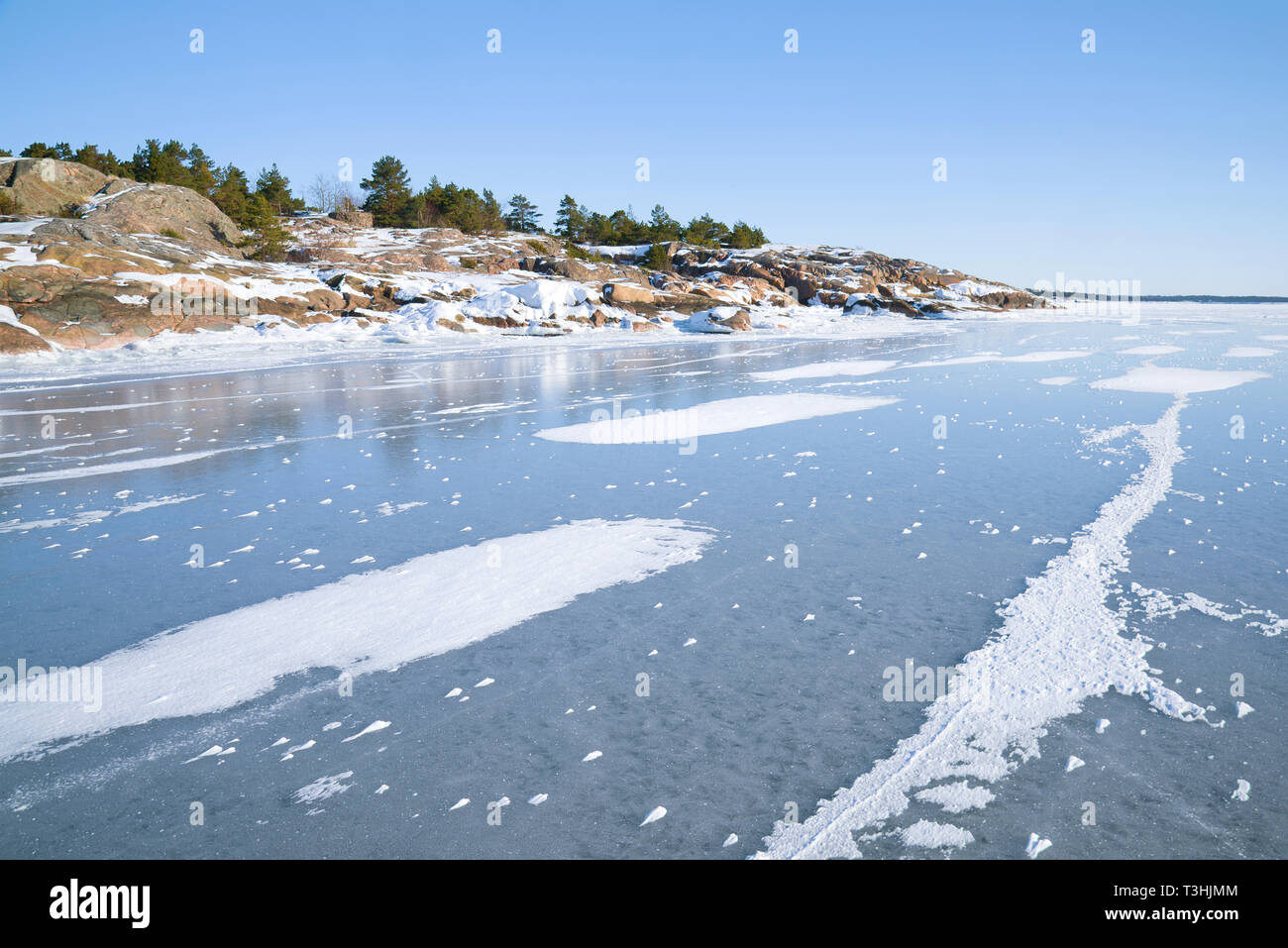 On ice of the innish Bay at the coast of the Hanko peninsula in the sunny February afternoon. Finland Stock Photo