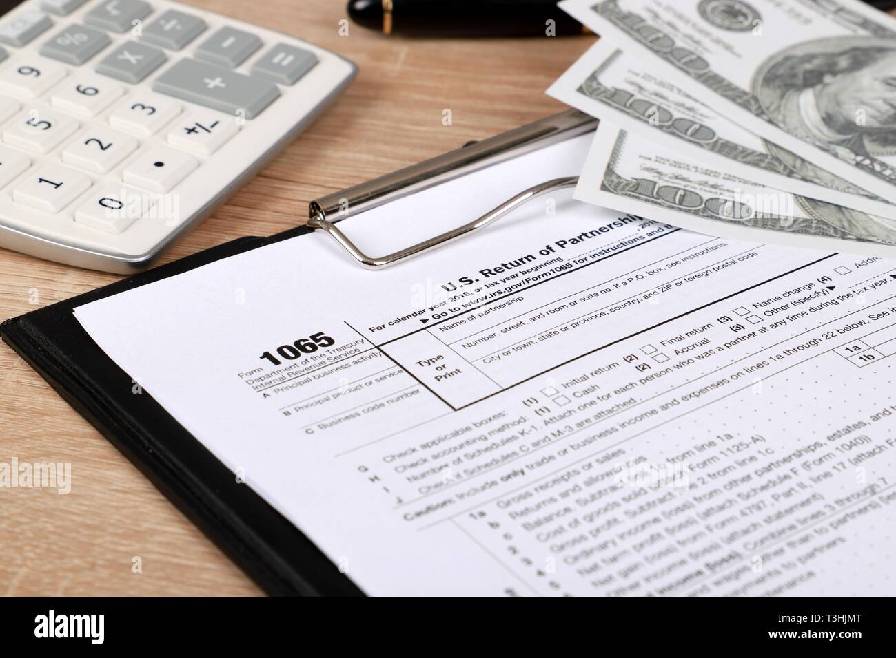 1065 tax form lies near hundred dollar bil and calculator  on a Table. US Return for parentship income Stock Photo