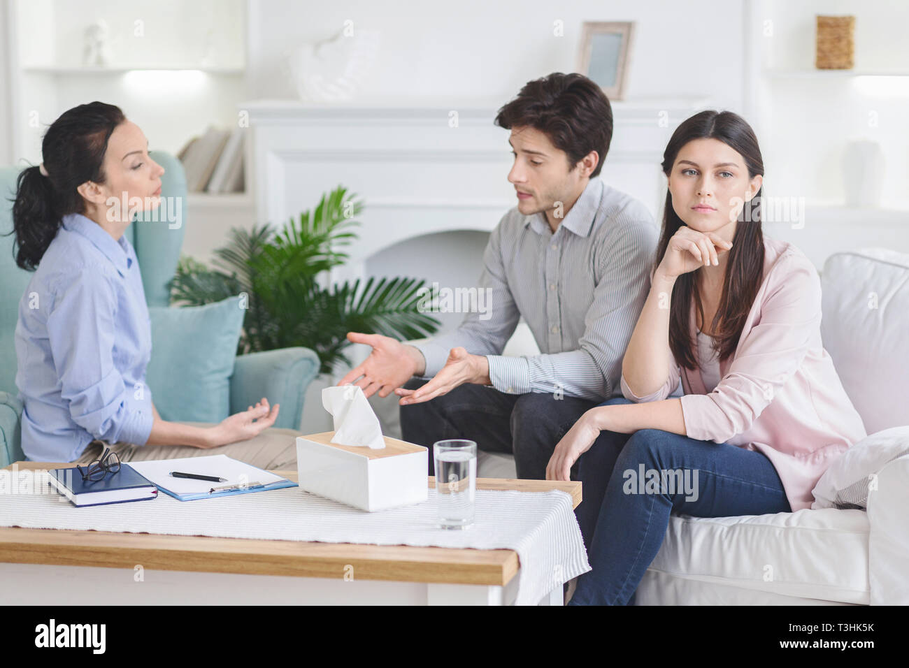 Upset man talking to psychiatrist during couple counseling session Stock Photo