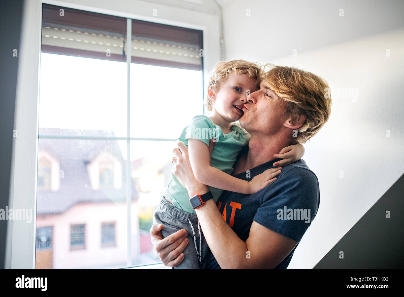 A happy father with a toddler son at home, kissing. Stock Photo