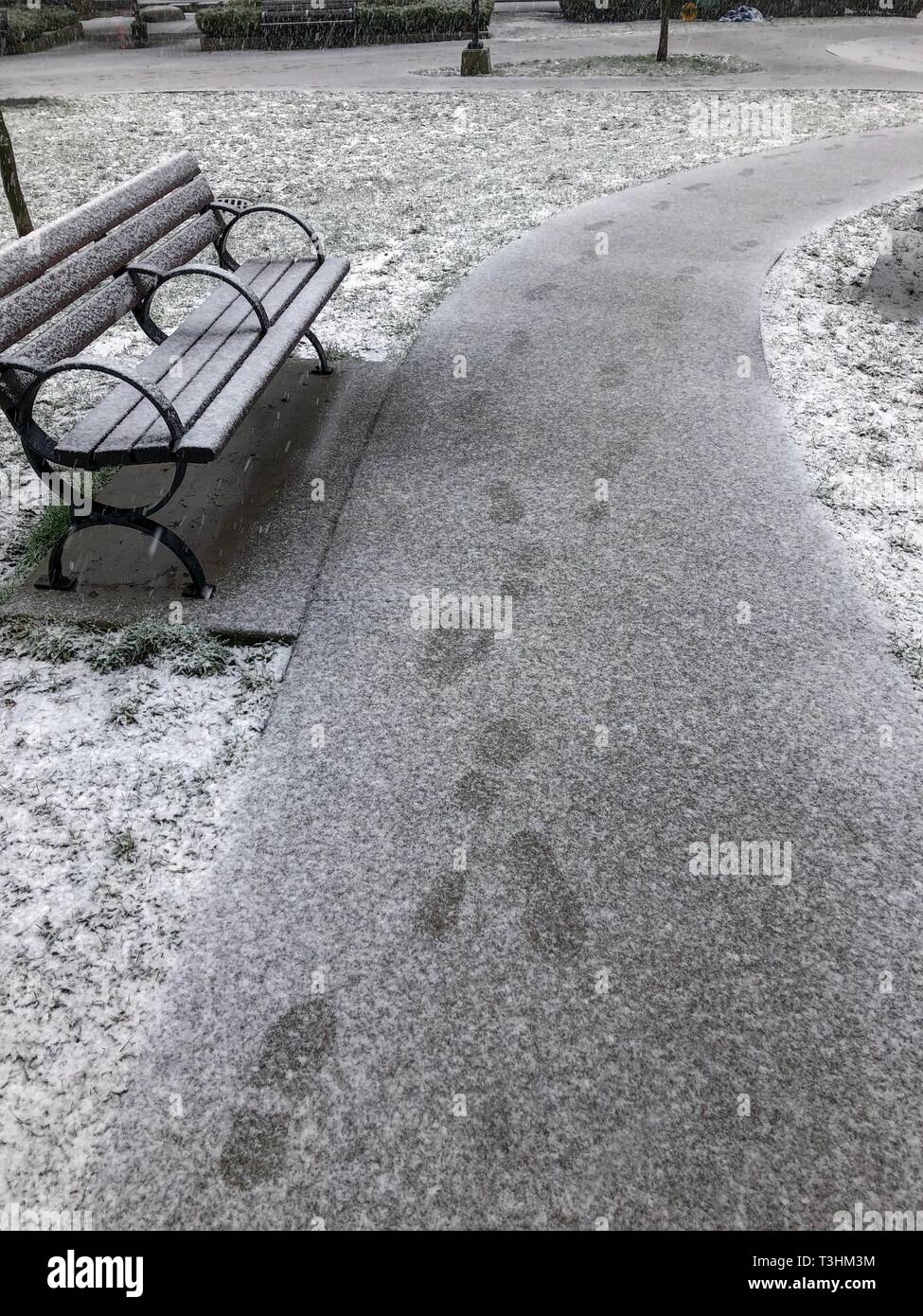 Bench and footsteps in mild snow Stock Photo