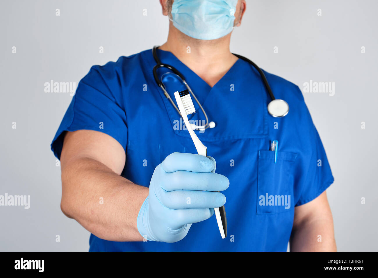 Doctor in sterile latex gloves and blue uniform holding a toothbrush