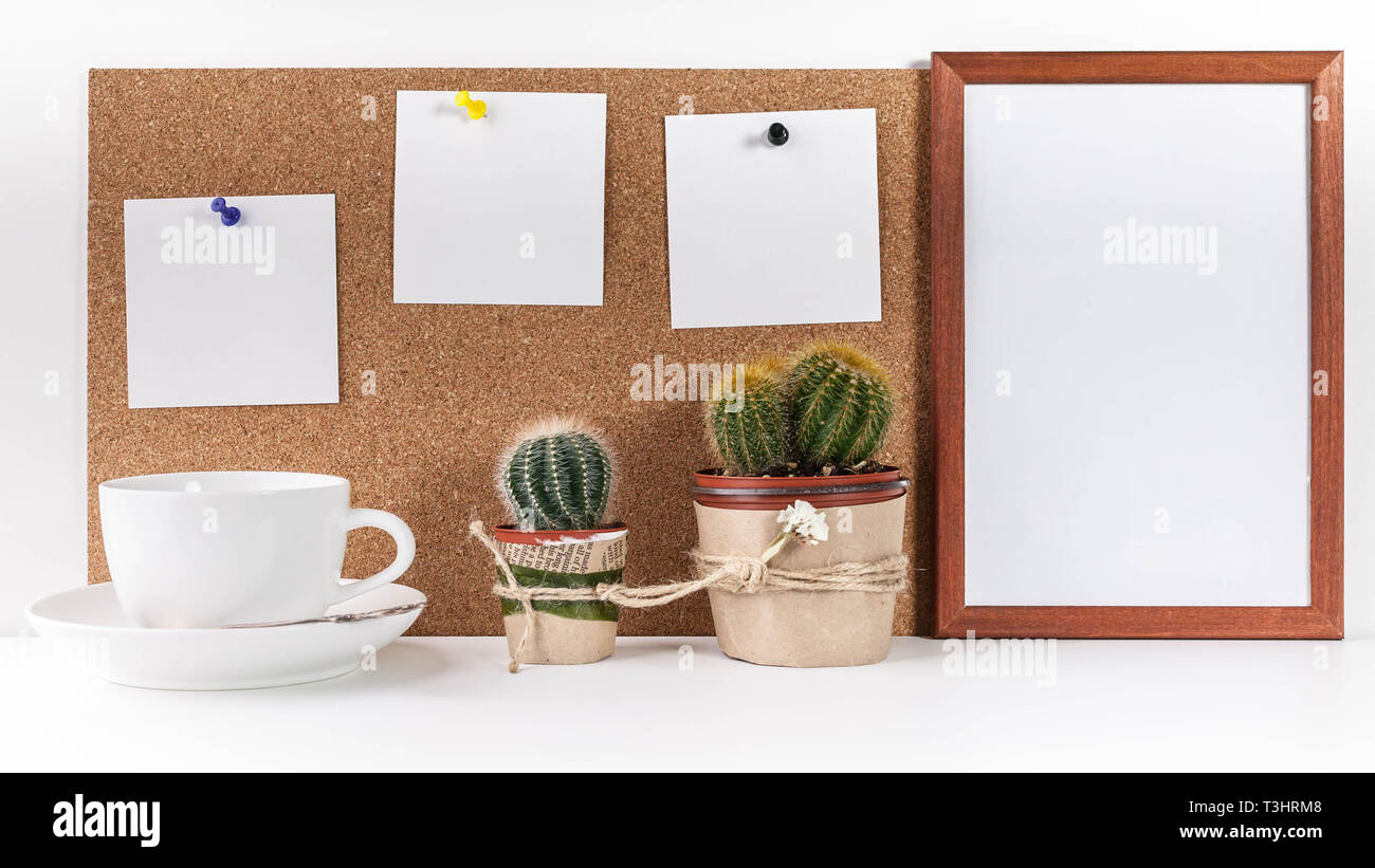 Workplace Mockup. Banner. Three white stickers, empty vertical frame, white cup, two cactus on a white background. Stock Photo