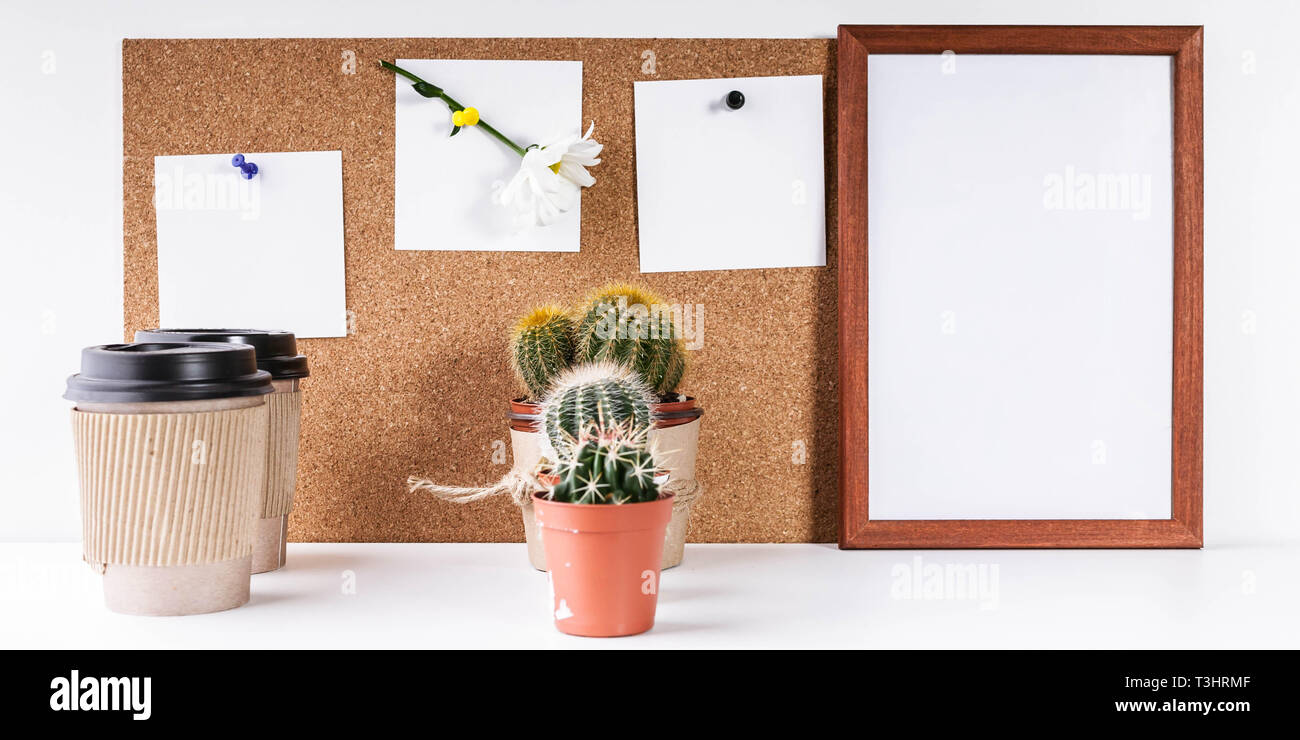 Workplace Mockup. Scandinavian style banner. Three white stickers, empty vertical frame, two cups of coffee, two cactus on a white background. Stock Photo