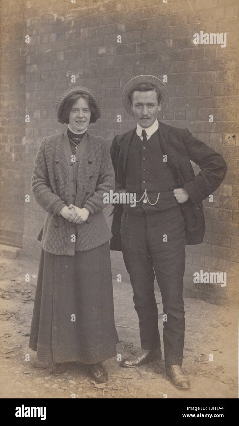 Vintage Photographic Postcard Showing a Fashionable Young Lady and a Dapper Gentleman Posing Outdoors. Stock Photo