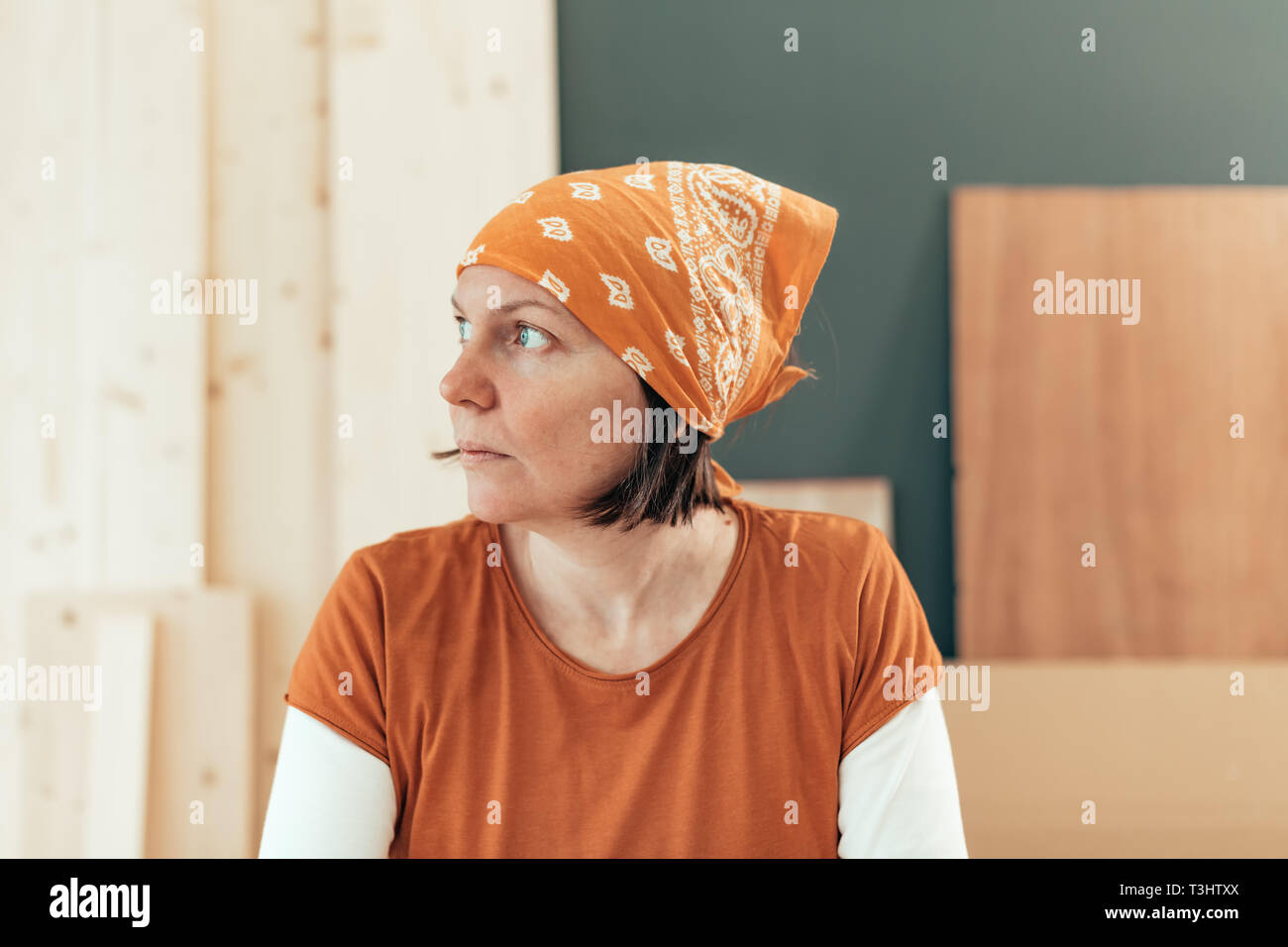 Self employed female carpenter looking out the window portrait in her small business woodwork workshop Stock Photo