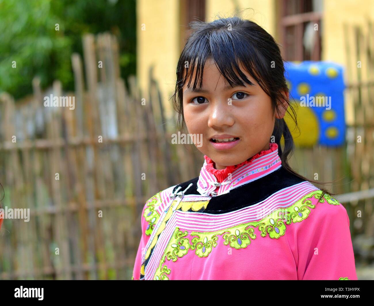 Pretty Miao girl (Chinese ethnic minority) wears a pink traditional ethnic costume and poses for the camera. Stock Photo