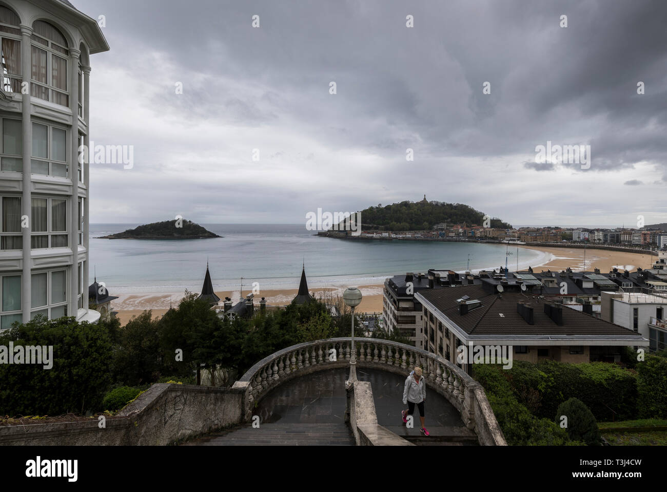 Woman walking down a set of stairs with the view of one of San Sebastián's bays in the background. Stock Photo