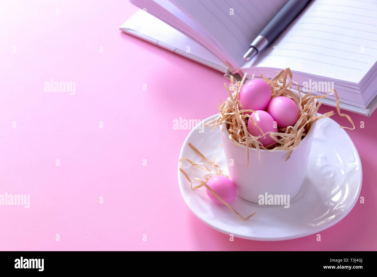 Small pink candy eggs in the cup. Easter celebrate concept. Pink background. Almonds in sugar coating. Copy space. Stock Photo