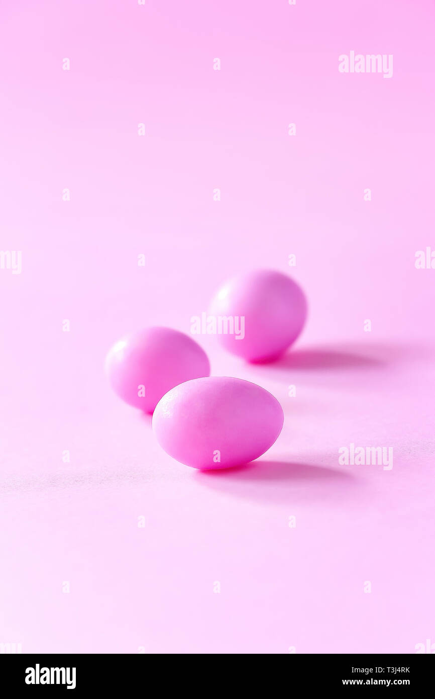 Three small pink eggs on pink background. Easter celebrate concept. Copy space. Stock Photo