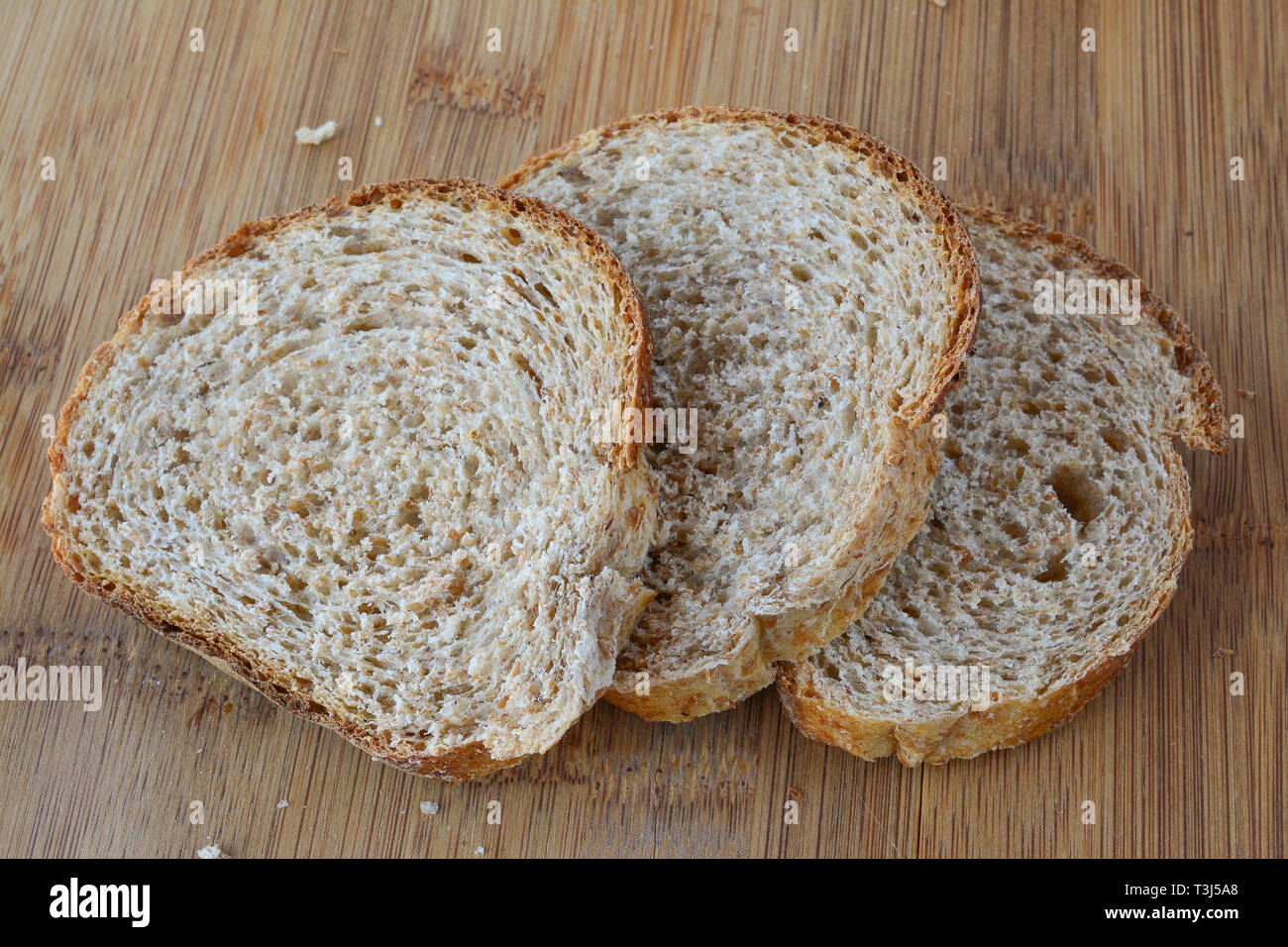 Three slices of dark, integral  bread, delicious and healthy, on bamboo wooden chopping board, close up view Stock Photo