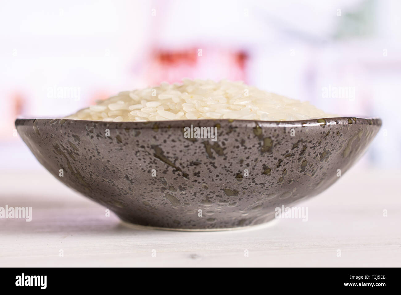 Lot of whole white jasmine rice grains on grey ceramic plate in a white