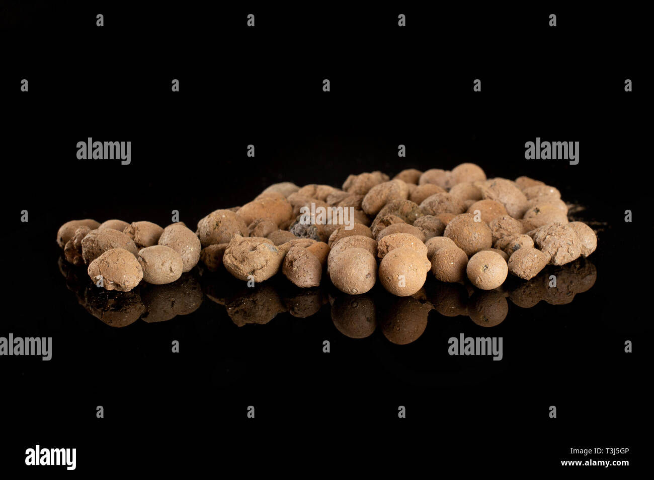Lot of whole brown clay pebbles (leca) isolated on black glass Stock Photo