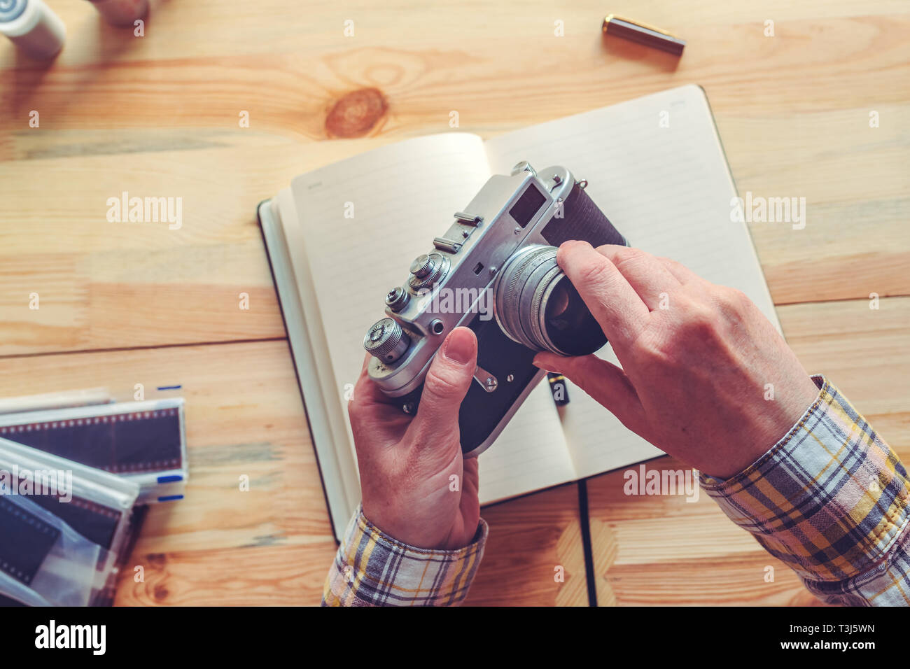 Photographer changing lens on vintage film photography camera in studio