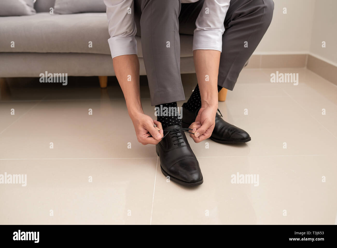Man's hands tying shoelace of his new shoes. People, business, fashion and footwear concept - close up of man leg and hands tying shoe laces. Stock Photo