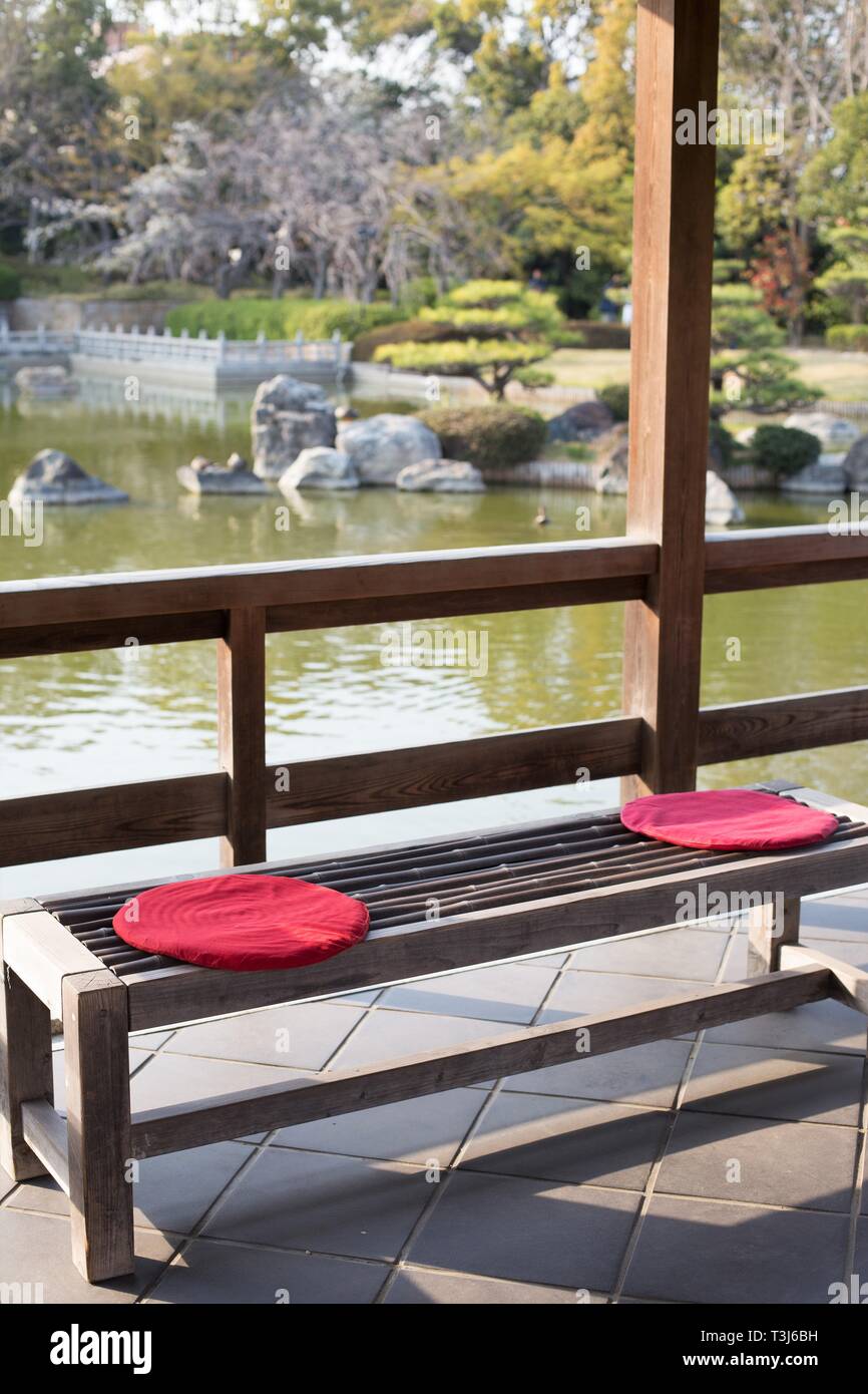 A bench with cushions next to a pond in the Japanese garden in Daisen