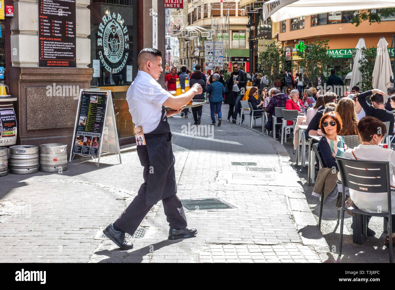 People outside Tapas Bar Birra & Blues, sidewalk street view with the waiter serving drinks Valencia cafe Valencia Spain Europe Stock Photo
