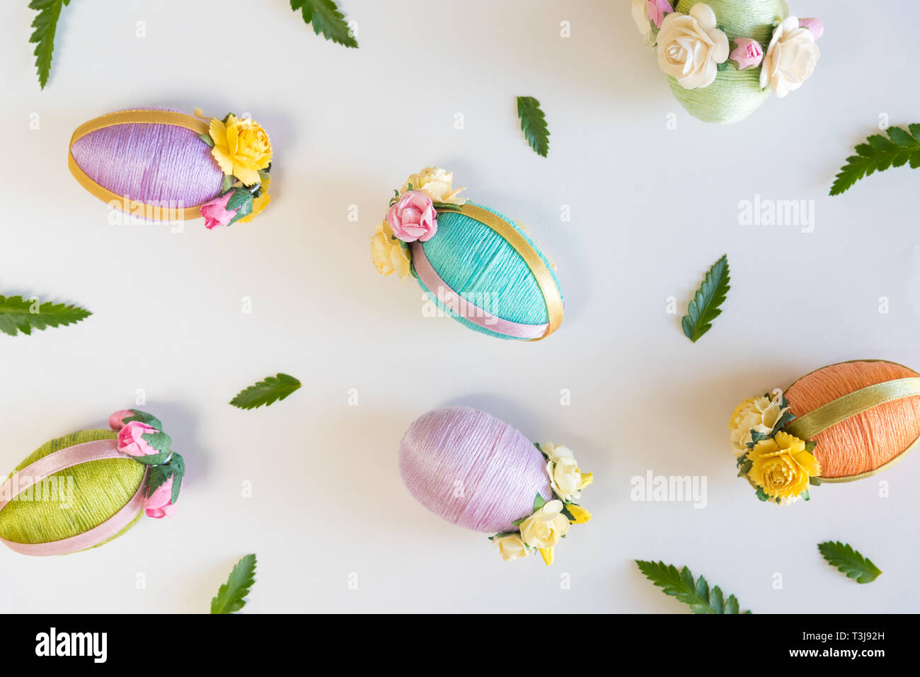 Easter eggs and small green leaves arranged on white background Stock Photo