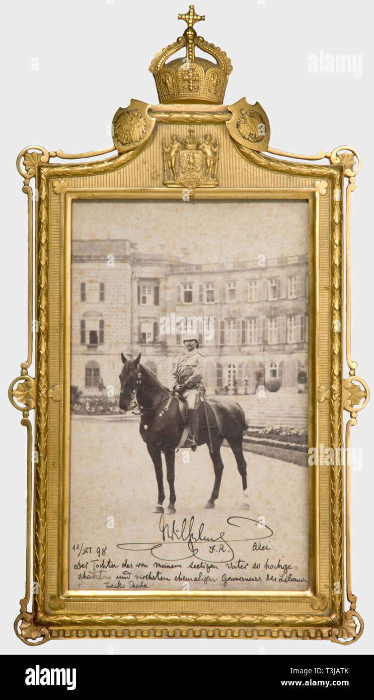 Kaiser Wilhelm II, a dedication photograph in a presentation frame, Baalbek/Lebanon, 11 October 1898 A large size photograph of Kaiser Wilhelm II on horseback in the Uniform of the imperial 'Schutztruppe'. On the lower edge a signed and dated dedication in ink (transl.) 'Wilhelm I.R. - 11/XI.98 - To the daughter of, by my late father so very admired and adored, governor of the Lebanon, Franko Pascha'. On the photo the stamped date '1898'. Foxed. In a fire-gilt, splendid brass frame with laurel border surmounted by the imperial crown, flanked by the imp, Artist's Copyright has not to be cleared Stock Photo