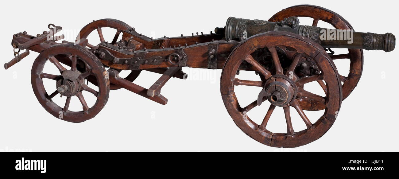 A Southern German model cannon, circa 1700. Bronze barrel with a cannon muzzle (bottom dented) of high quality craftsmanship, sectioned by rich scrollwork with acanthus leaves, scales, and chain decoration in half relief. Trunnions on the sides, and a dolphin-shaped handle on top in front of a coat of arms for the Franconian Fechenbach noble family. Sculpted cascabel on the breech. Oak carriage with iron mountings. Barrel length 59 cm. Total length 99 cm. Also the matching limber, 19th century(?). Total length with limber 135 cm. historic, histor, Additional-Rights-Clearance-Info-Not-Available Stock Photo