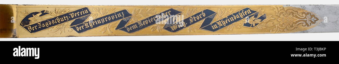 A deluxe presentation hunting hanger, Cologne, circa 1900/1910 A single-edged blade with a double-edged point. The upper two-thirds covered with etched and gilded decoration. An inscription scroll on the obverse side bearing the dedication, 'Der Jagdschutz-Verein der Rheinprovinz dem Revierjäger Wilh. Storb in Rheindassen' (from the Rhine Province Game Protective Association to Game Keeper Wilh. Storb in Rheindassen). The opposite side depicts wild game. The back of the blade bears the maker's inscription, 'Kettner Köln a/Rhein'. Sculpted gilded , Additional-Rights-Clearance-Info-Not-Available Stock Photo